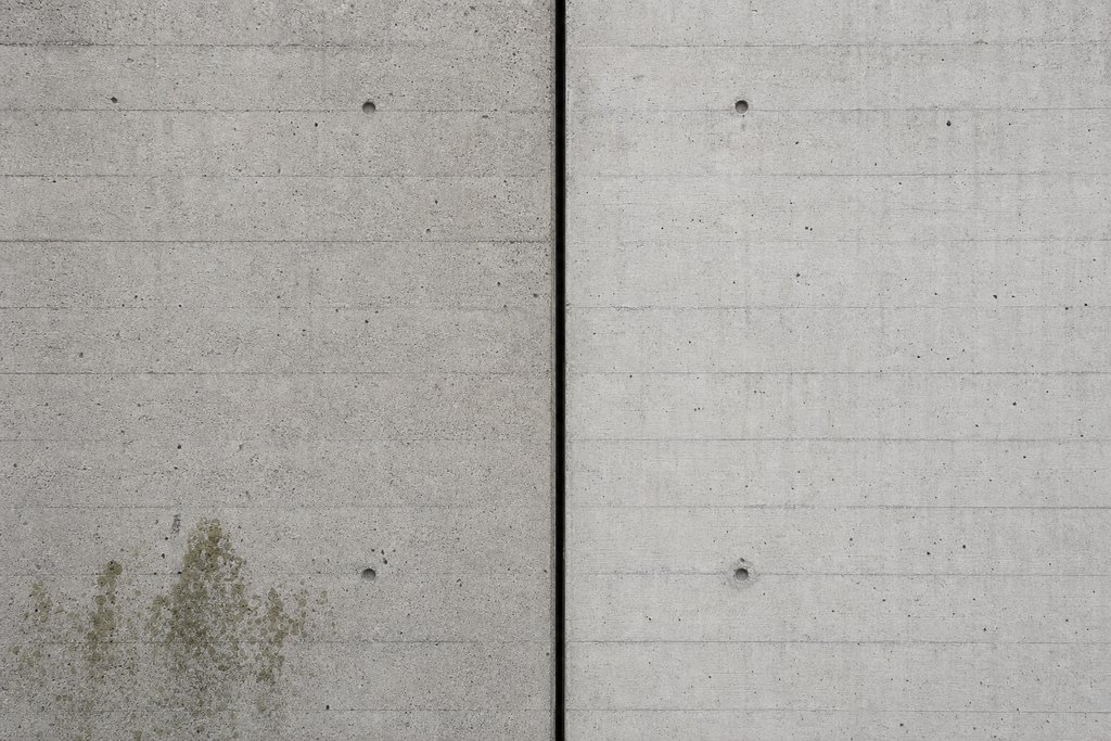 Two vast concrete slabs meeting at a single vertical expansion joint that falls into shadow.